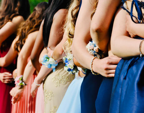 girls arm in arm with their prom dresses on
